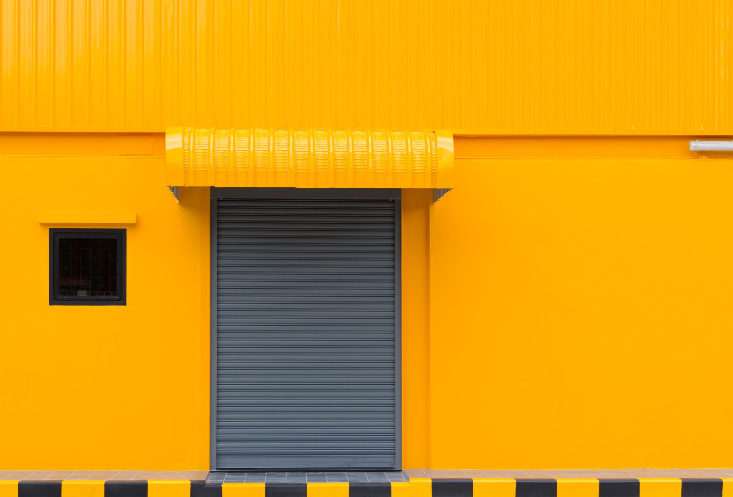 Yellow exterior warehouse with a grey door