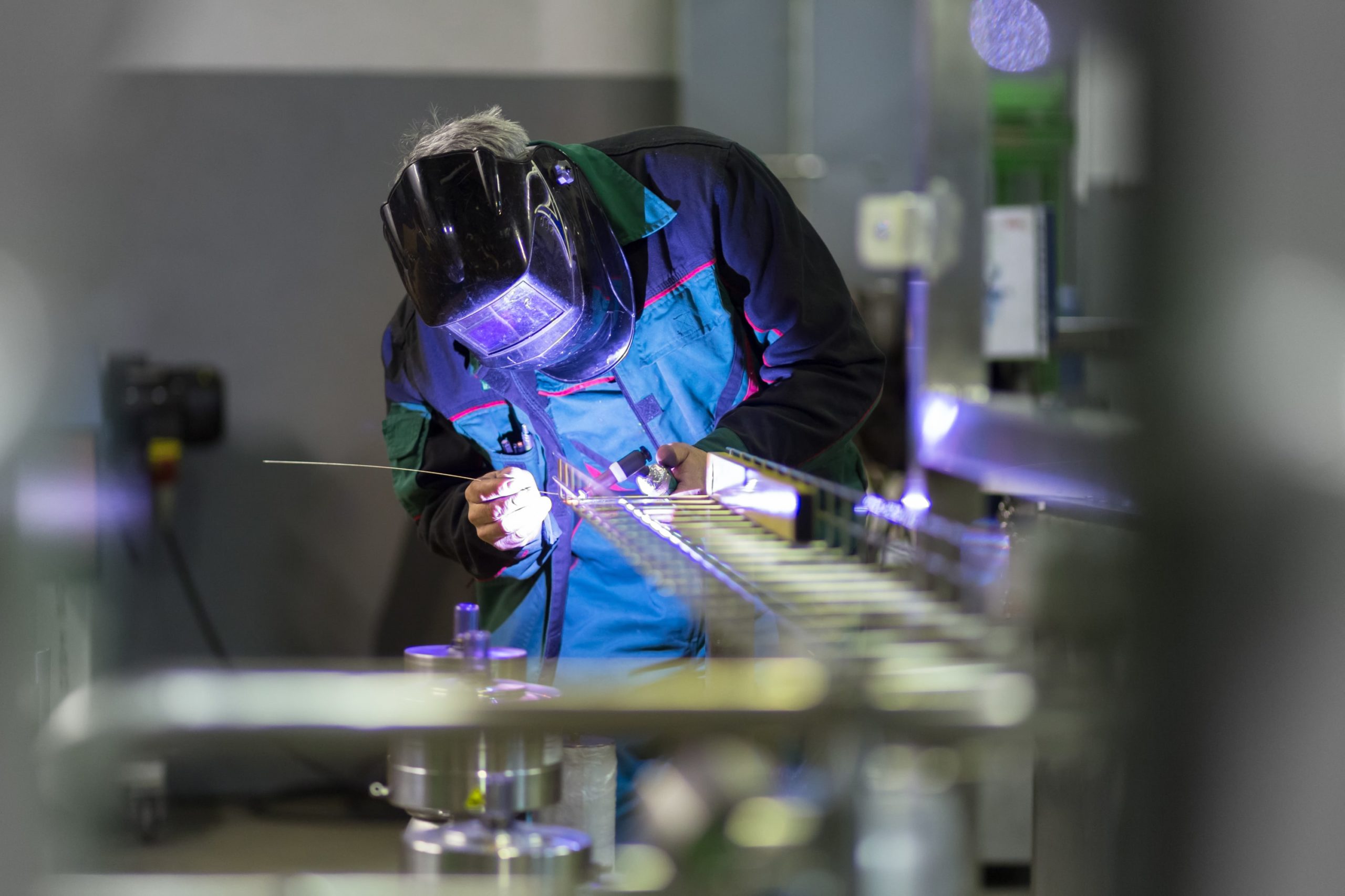 Welder working on a piece of metal in a manufacturing warehouse