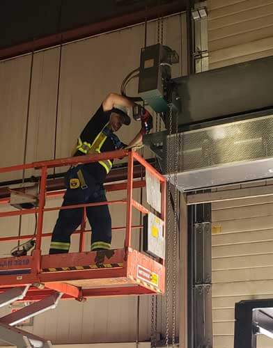 Technician on scissor lift installing an air curtain