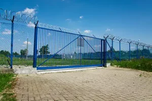 Blue security gate with a barbed wire fence