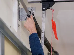 Man using wrench to tighten bolt on garage door spring