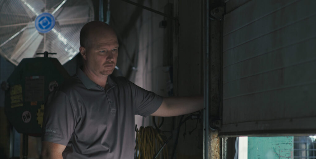 Wilcox technician inspecting the operation of a commercial overhead door in warehouse setting