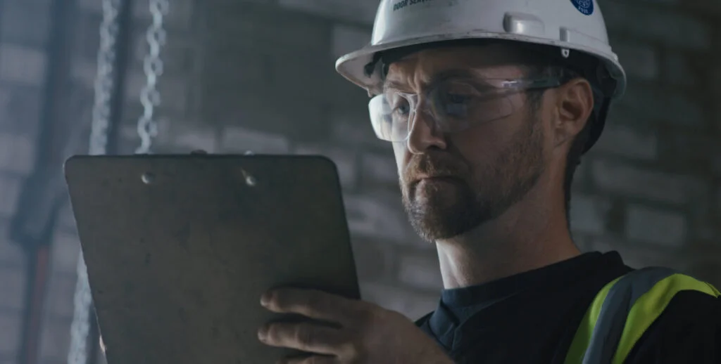 Technician in safety gear reviewing inspection checklist on a clipboard