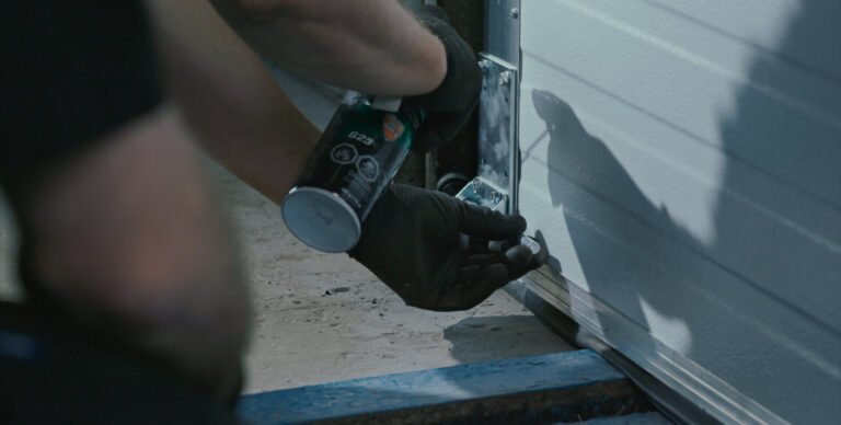 Wilcox technician lubricating overhead door hardware during routine commercial maintenance