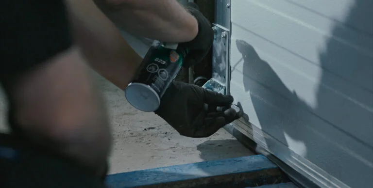 Wilcox technician lubricating overhead door hardware during routine commercial maintenance